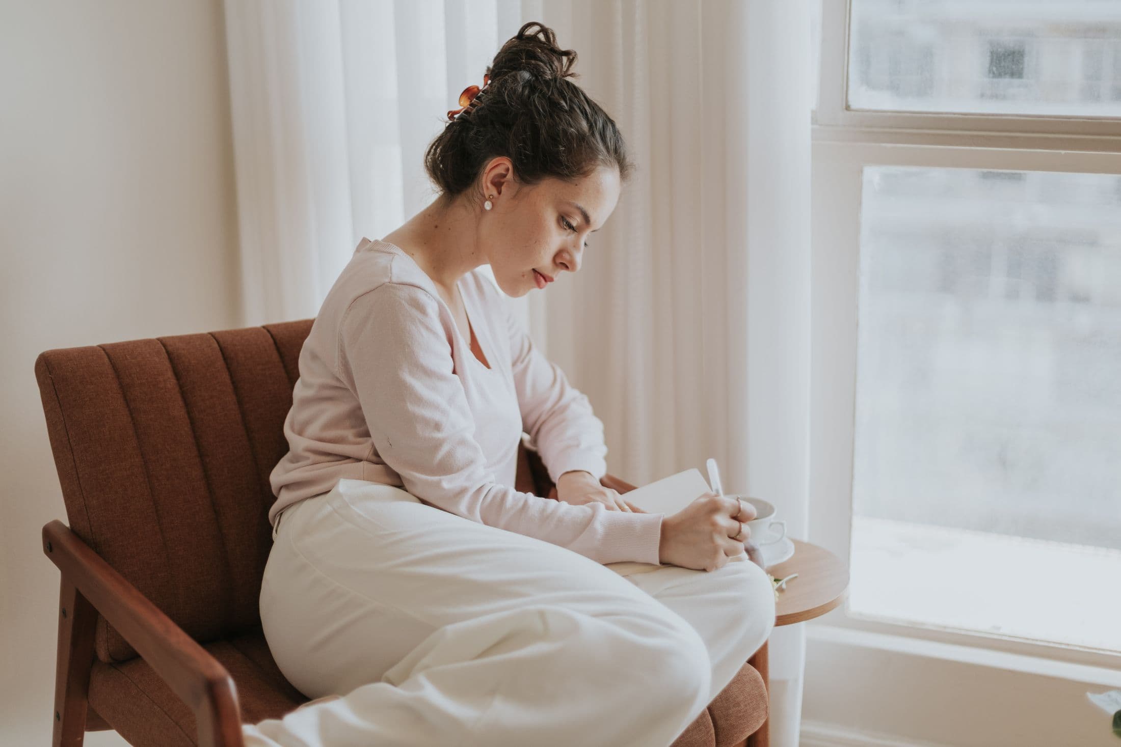 A person journaling quietly by a sunlit window